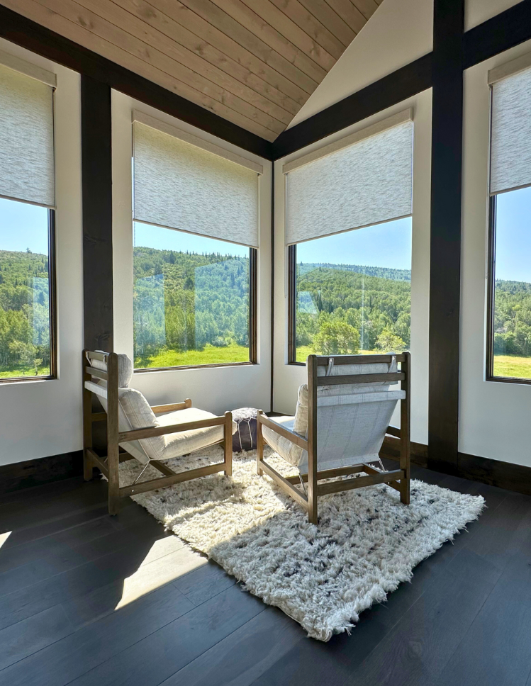 Window coverings over looking mountain with white chairs and white rug