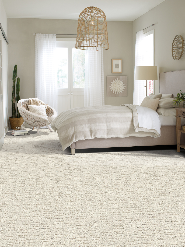 Off-white carpet, bedroom, side chair with pillow and blanket, windows.